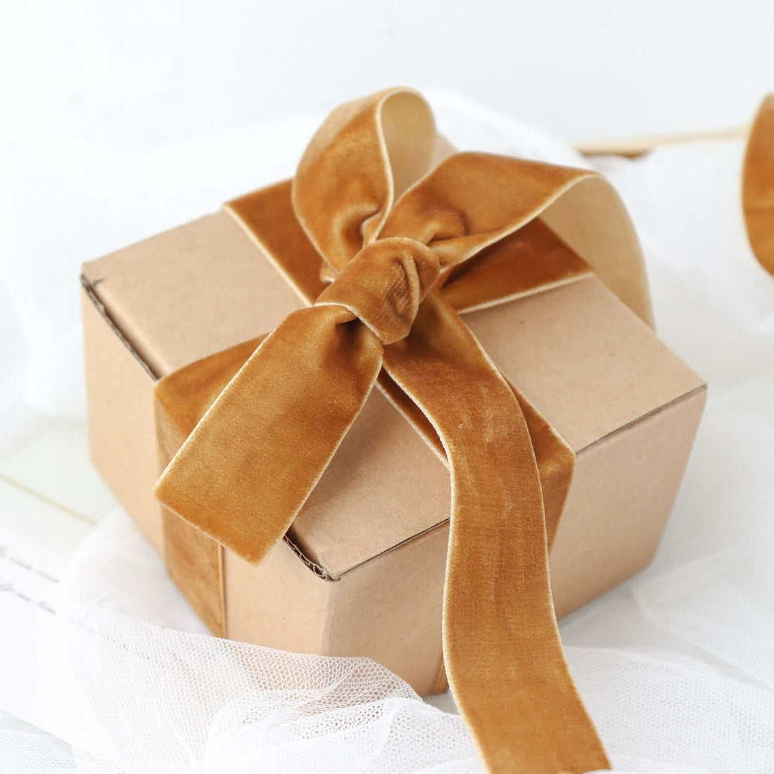 Brown gift box with a velvet ribbon bow on a light surface.