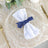 Elegant white napkin with navy ribbon on a decorative plate.