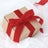 Brown gift box with red ribbon on white fabric background.