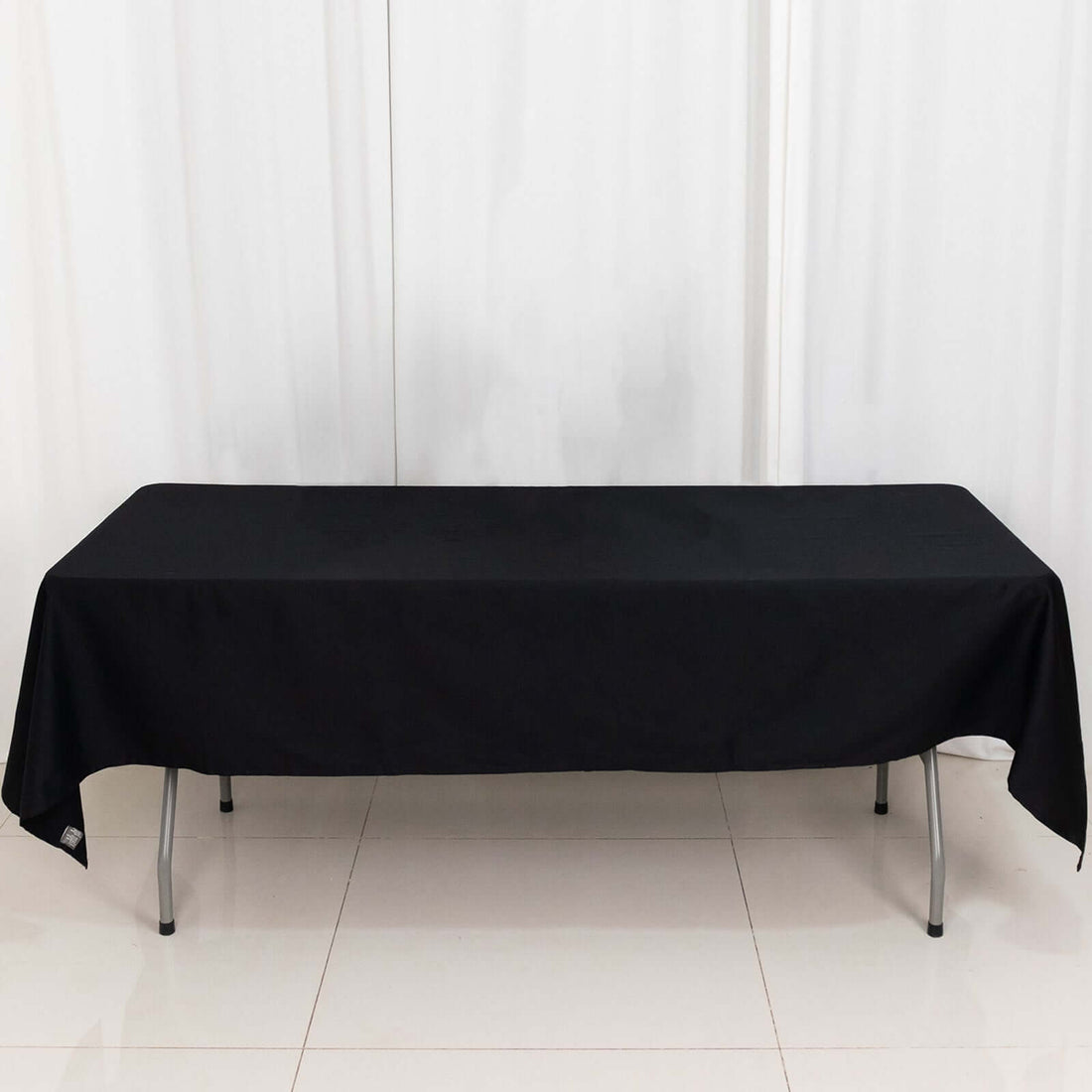 Black tablecloth draped over a long table in a studio setting.