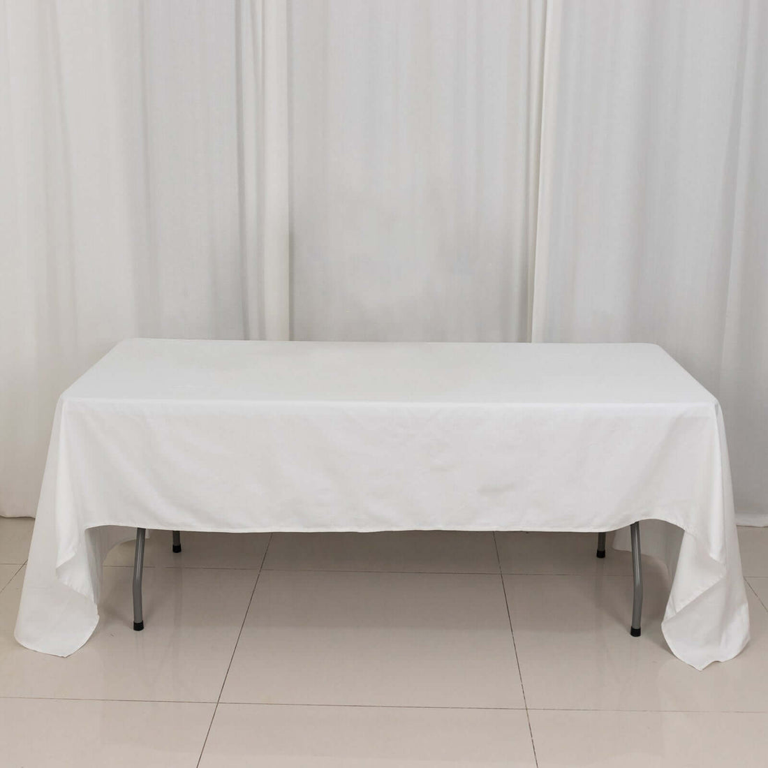 White table covered with a plain tablecloth in a studio setting.