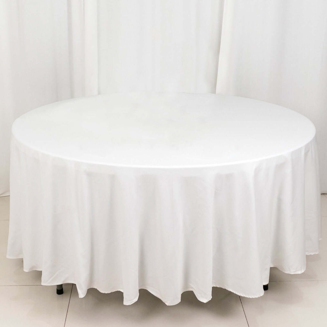 Round white table with a tablecloth on a plain background