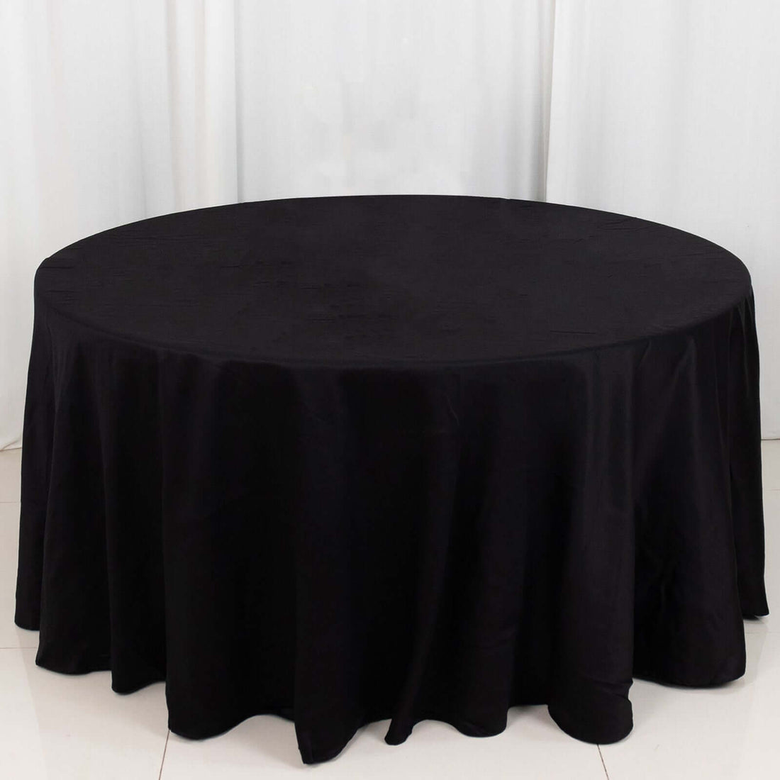 Black round tablecloth with elegant draping on a table.