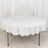 Round table with white tablecloth on a plain backdrop.