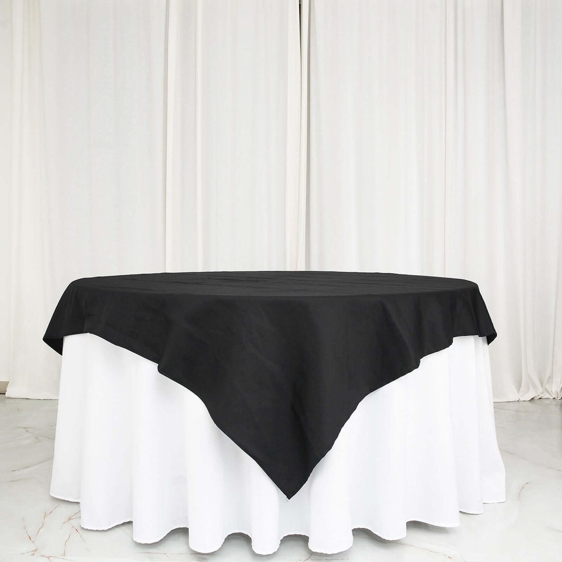 Black tablecloth draped over a round table with a white base.