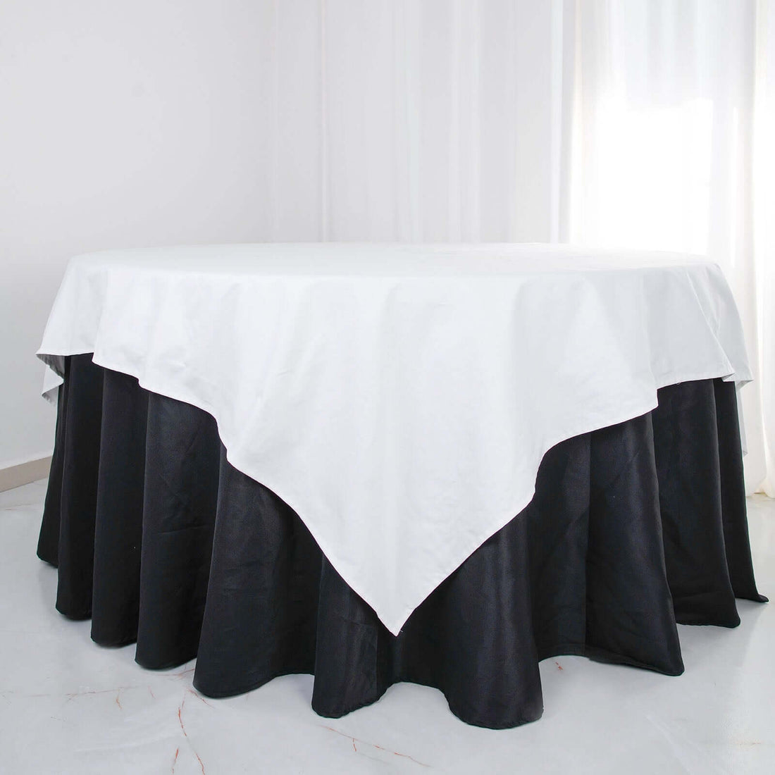 White and black tablecloth on a round table in a bright setting.