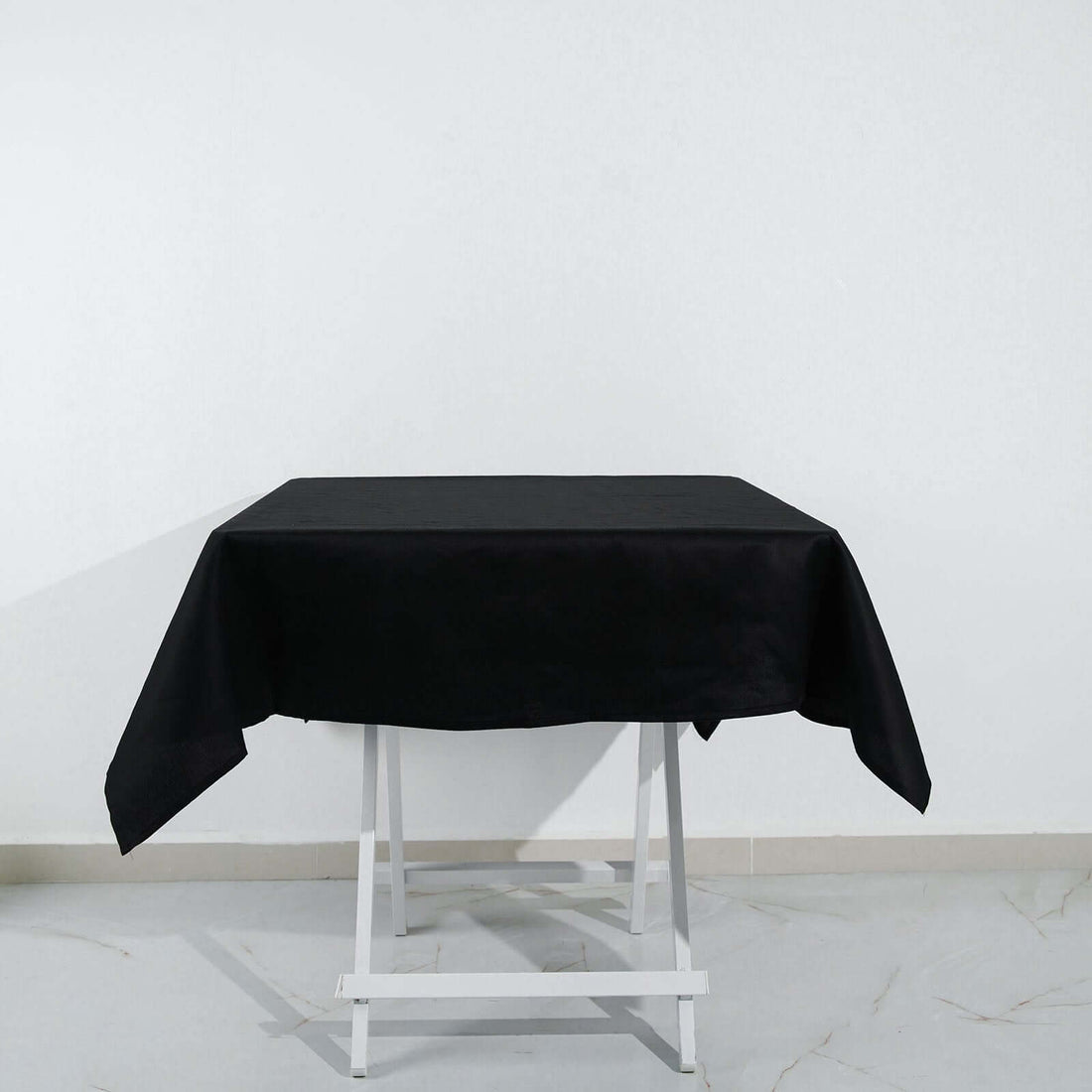 Black tablecloth on a white table against a plain white backdrop