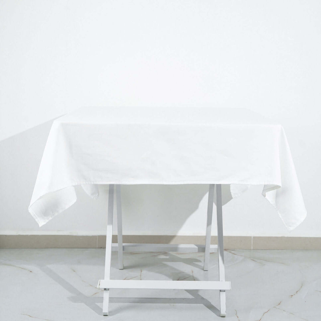 White tablecloth on a folding table against a plain background.