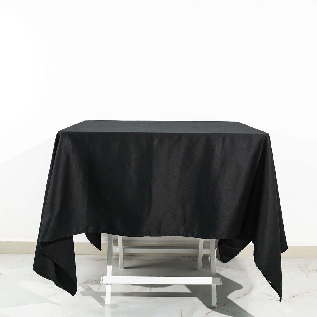 Black tablecloth draped over a white table on a plain white background