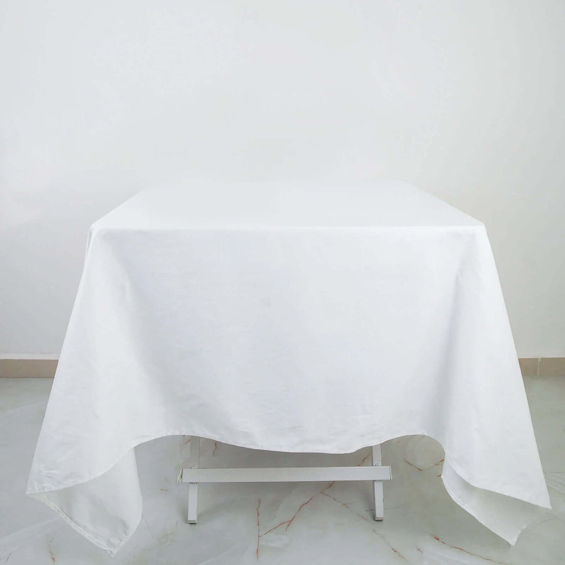 White tablecloth draping over a table in a studio setting.