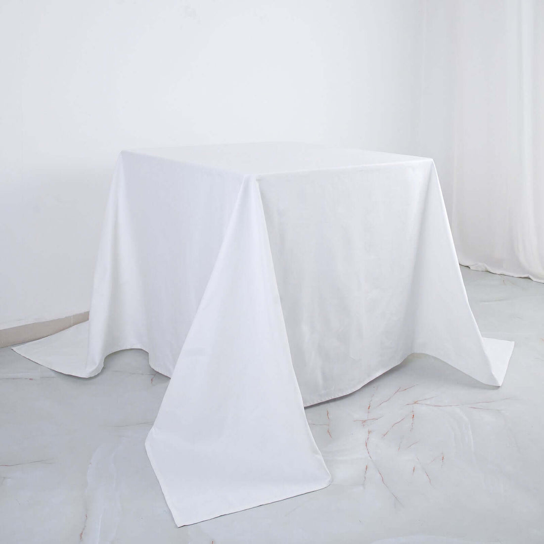 White table covered with a plain tablecloth on a studio backdrop
