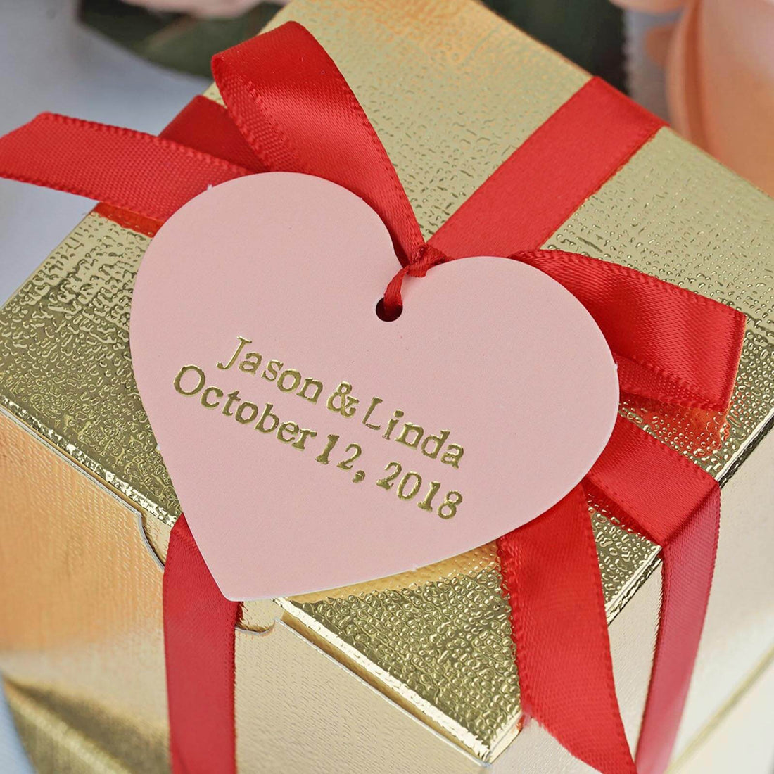 Gold gift box with red ribbon and heart tag for Jason & Linda's wedding date.