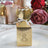 Gold gift box with floral design and ribbon, set on a decorative plate.