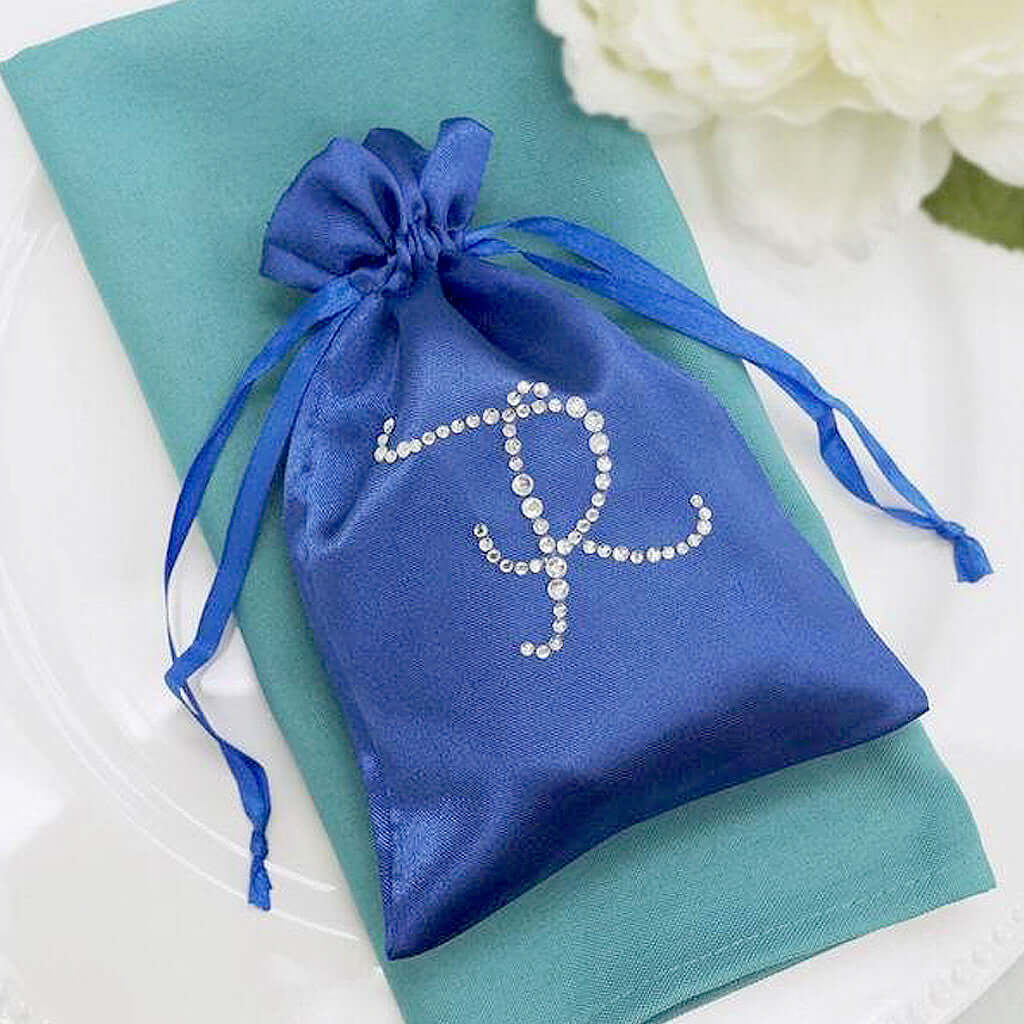 Blue satin pouch with rhinestone monogram on a teal napkin.