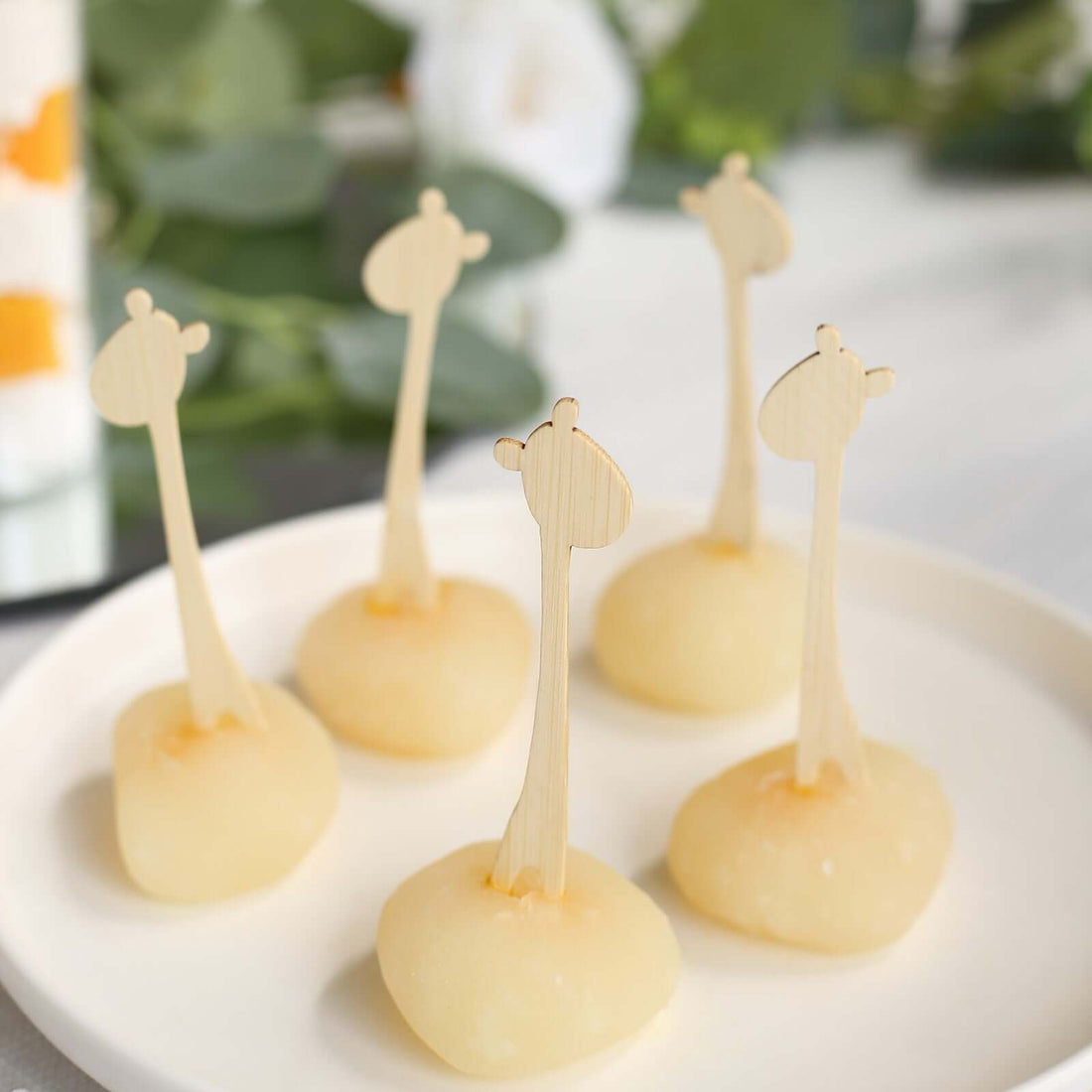 Giraffe-themed dessert bites on a plate with wooden sticks
