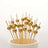 Gold cocktail picks in a cup on a white background.