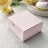 Pink gift box on a lace tablecloth with roses and dinnerware in the background.