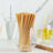 Bamboo straws in a clear glass container on a marble countertop.