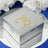 Silver gift box adorned with gold rhinestone design on a reflective surface.