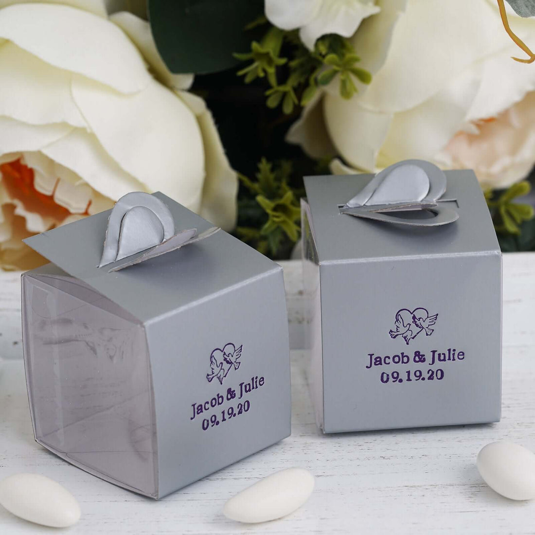 Personalized wedding favor boxes in silver with custom names and date.