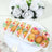 Decorative pastries in floral packaging on a white plate with roses.