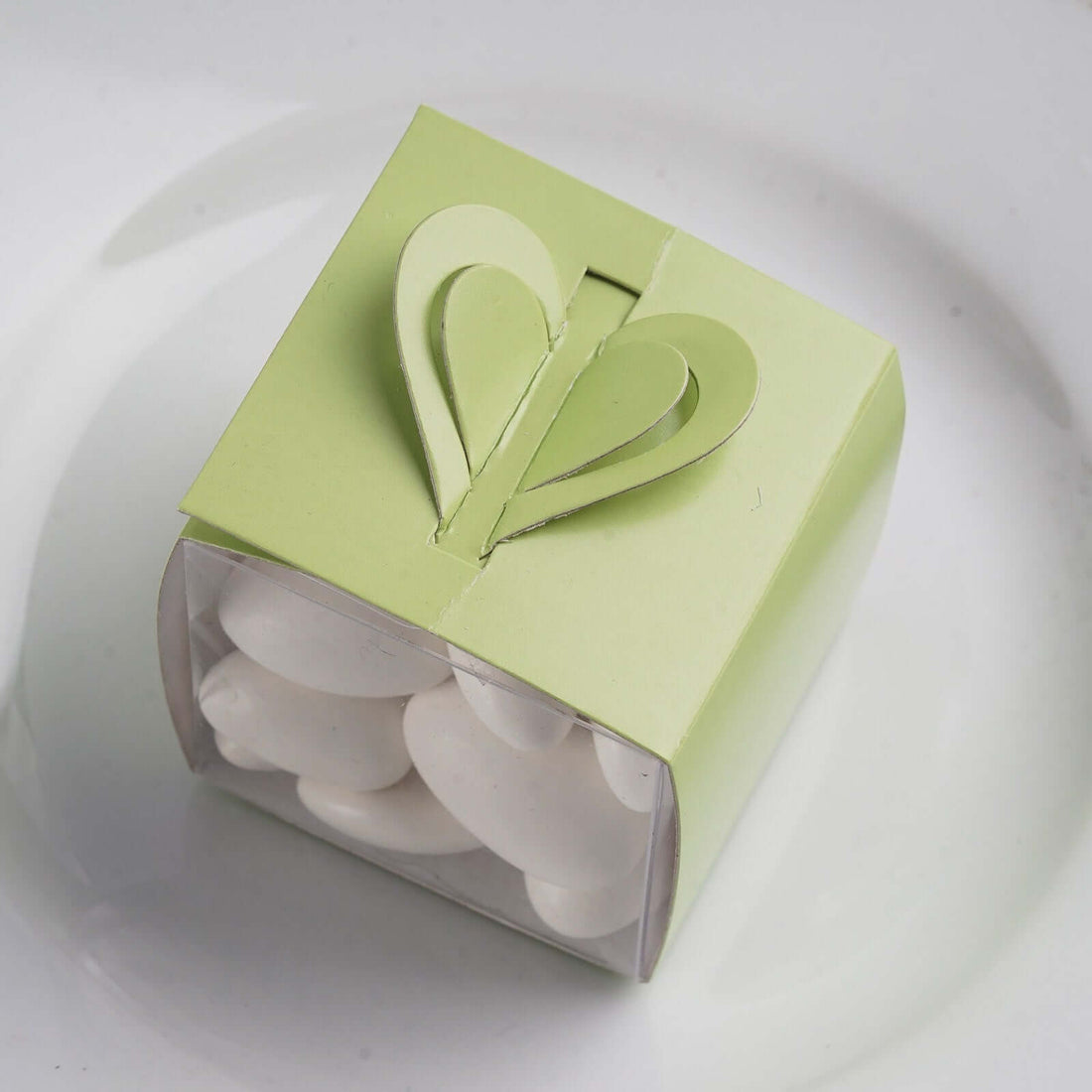 Green heart-shaped gift box with white candies inside.