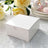 White gift box on a textured table with roses and plates.