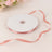 Pink satin ribbon on a spool with a loose end