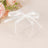 Clear gift box with a white ribbon, surrounded by soft floral accents.