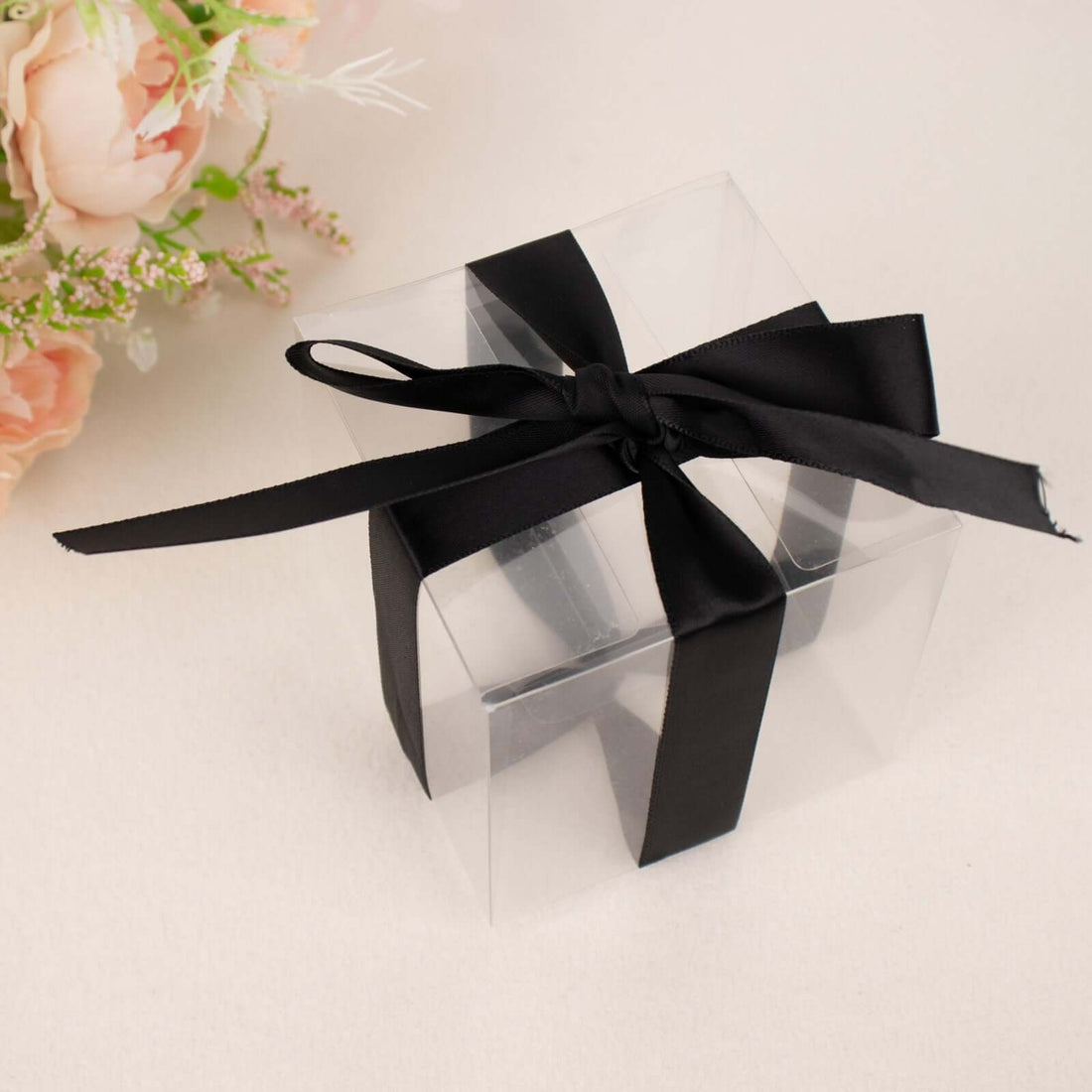 Clear gift box with a black ribbon bow on a soft background.