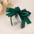 Clear gift box with a dark green satin ribbon on a neutral background.