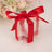 Clear gift box with a red ribbon and bow, surrounded by soft floral decor.