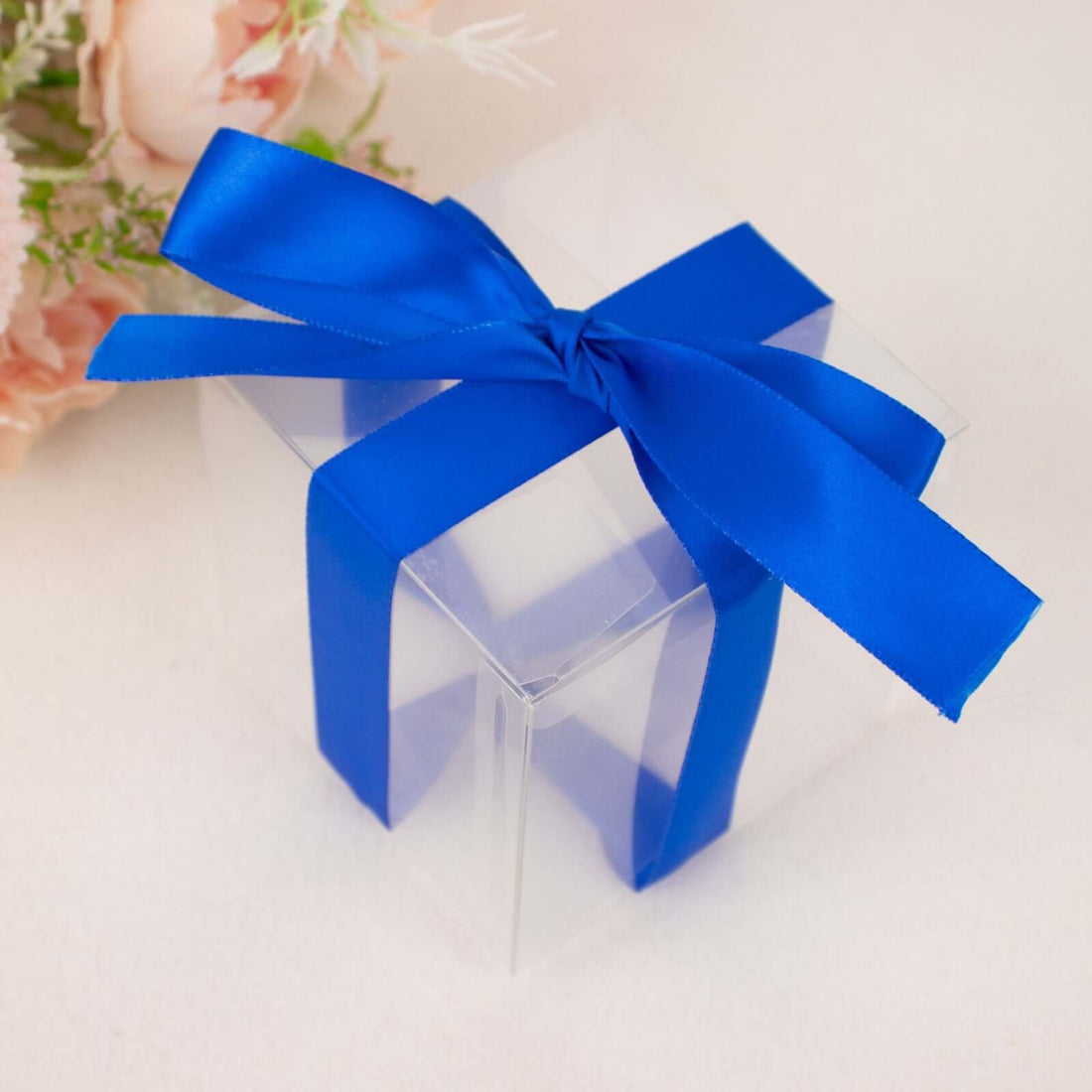 Clear gift box with a blue satin ribbon bow on top.