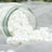 White decorative pearls spilling from a glass jar on soft fabric.