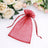Red organza gift bag with drawstring, surrounded by floral arrangement.