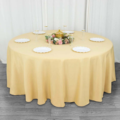 Round table set with yellow tablecloth and floral centerpiece.