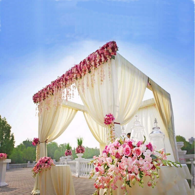 Elegant wedding canopy with floral draping and decorative table arrangement.