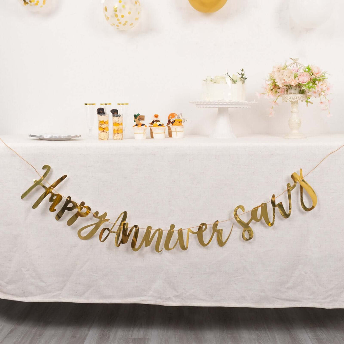 Gold "Happy Anniversary" banner at a decorated celebration table.