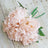 Pink peony bouquet with green leaves on a wooden background.