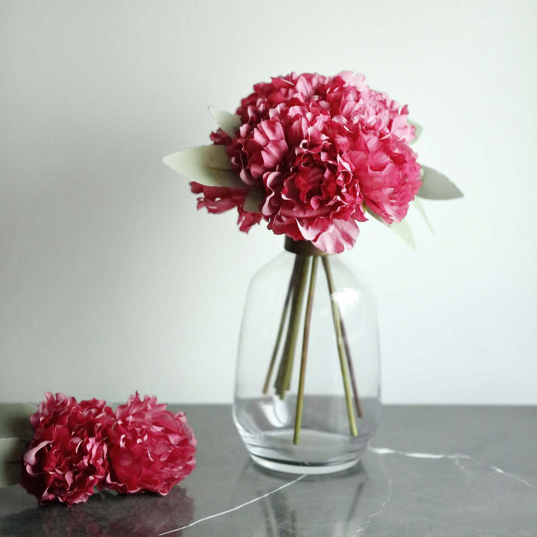 Pink floral bouquet in a clear vase with green leaves.