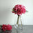 Pink floral bouquet in a clear vase with green leaves.