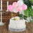 Birthday cake decorated with pink balloons and a golden "Happy Birthday" topper.