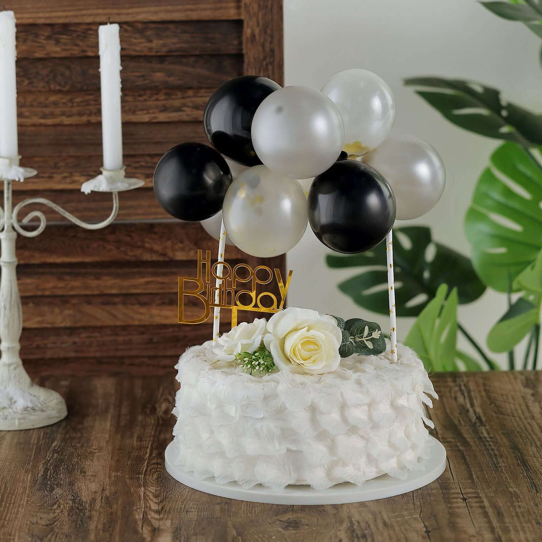 Birthday cake with balloons and flowers on a wooden table.