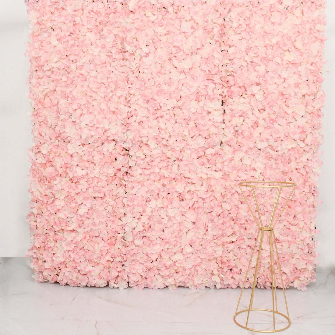 Gold geometric plant stand against a pink floral backdrop.