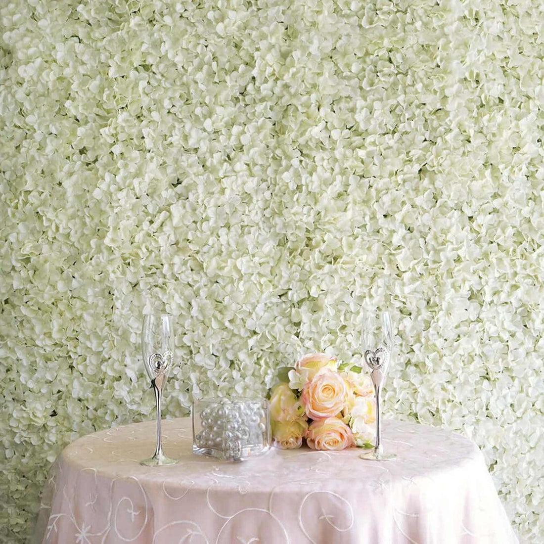 Elegant floral backdrop with champagne glasses and roses on a table.
