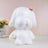 White dog-shaped figurine with floral accents on a soft pink backdrop.