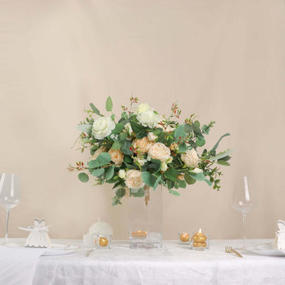Elegant floral centerpiece in a glass vase with greenery and roses.