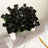 Black artificial rose bouquet in a clear vase with decorative accents.
