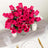Vibrant pink rose bouquet centerpiece with candles on a dining table.