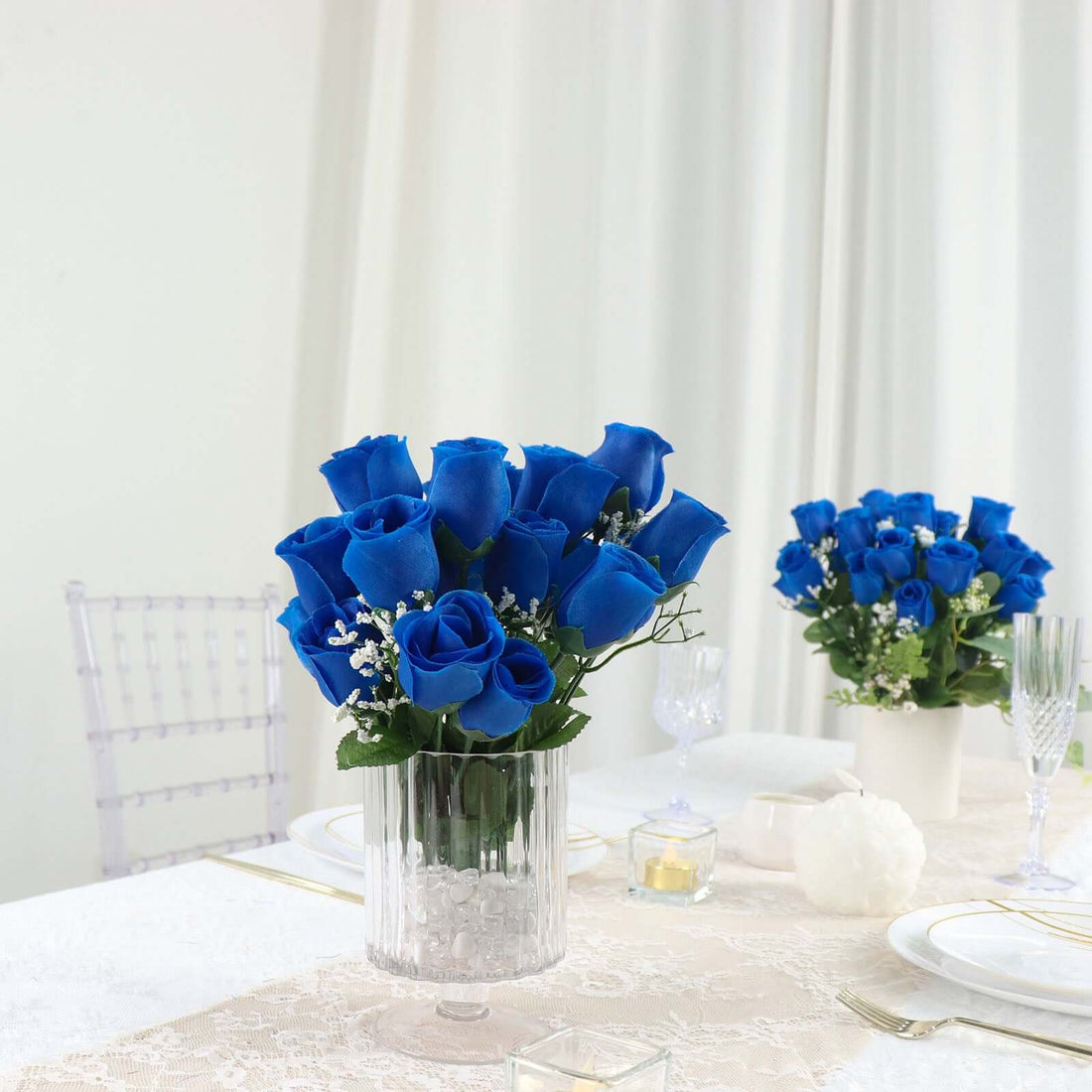 Blue rose bouquet in a clear vase on an elegantly set table.